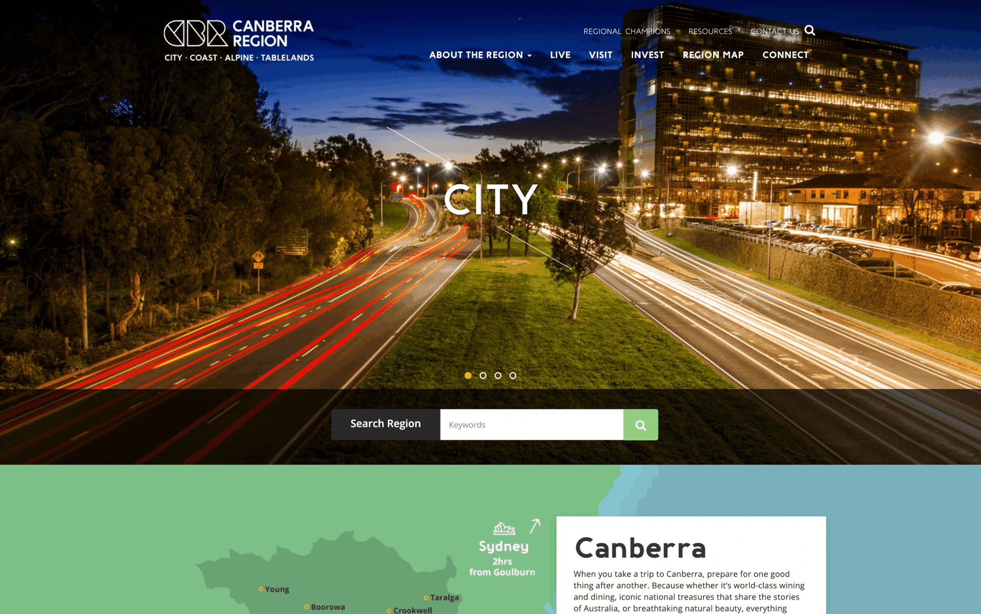 Nighttime city highway with light trails, trees, and a tall illuminated building in Canberra.