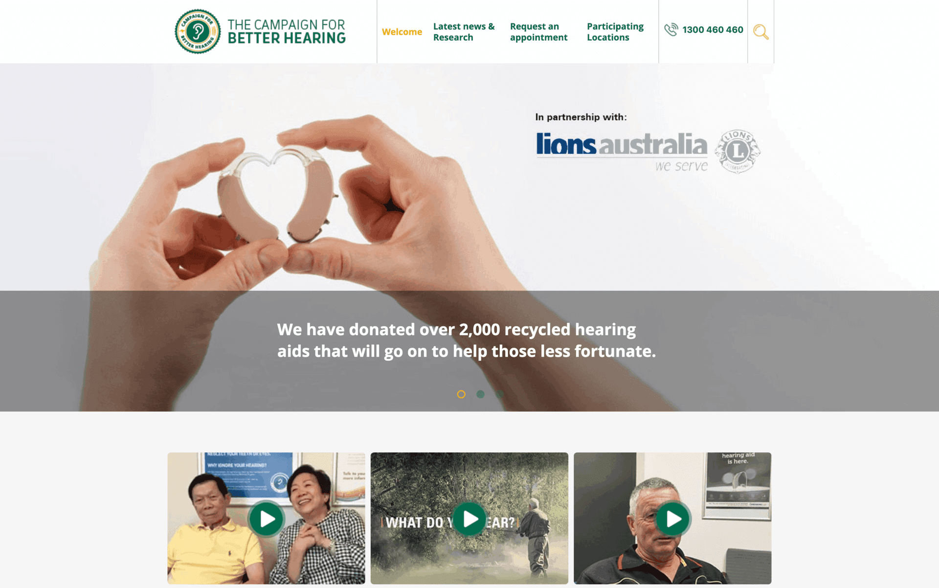 Hands holding two hearing aids shaped like a heart, promoting recycled hearing aids donation.