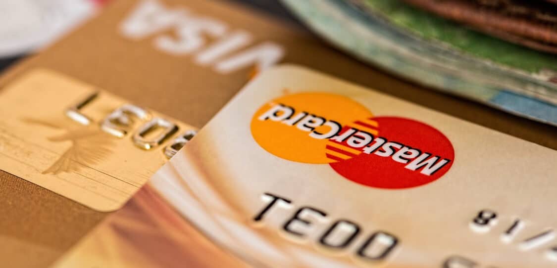 Close-up view of stacked Mastercard and Visa credit cards with embossed numbers visible.