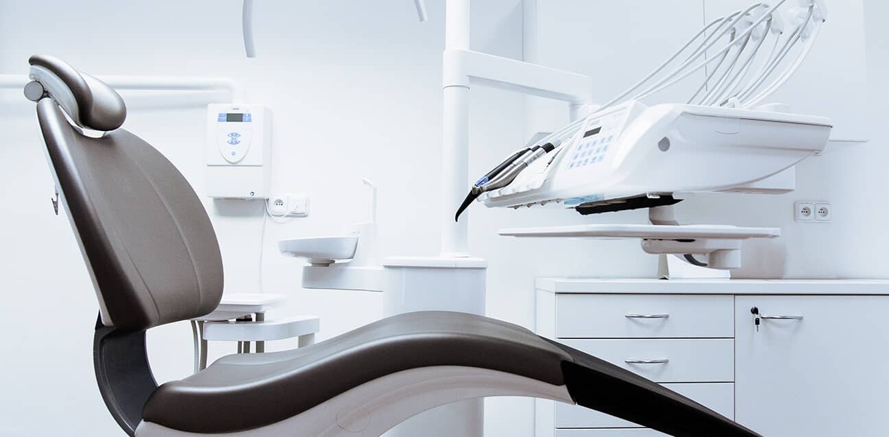 Modern dental chair and equipment in a clean, white dental clinic setting ready for patient treatment.