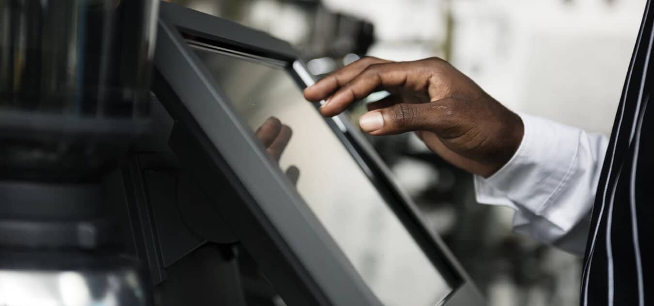 Hand interacting with a touchscreen monitor, possibly in a professional or service environment.