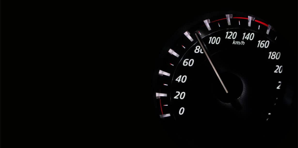 Car speedometer illuminated in dark, showing a speed around 55 km/h.