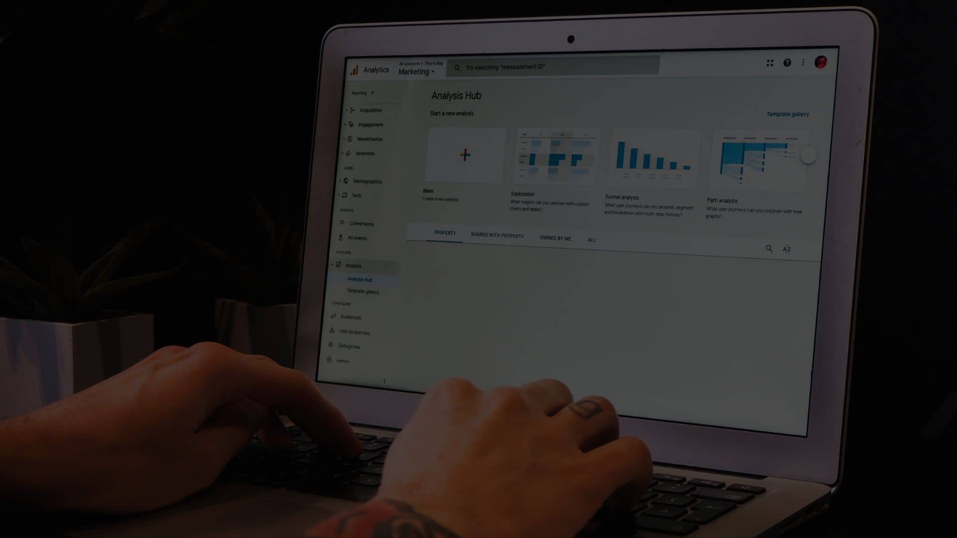 Person using web analytics tools on laptop to compare Google Analytics 4 upgrade benefits in dark room.