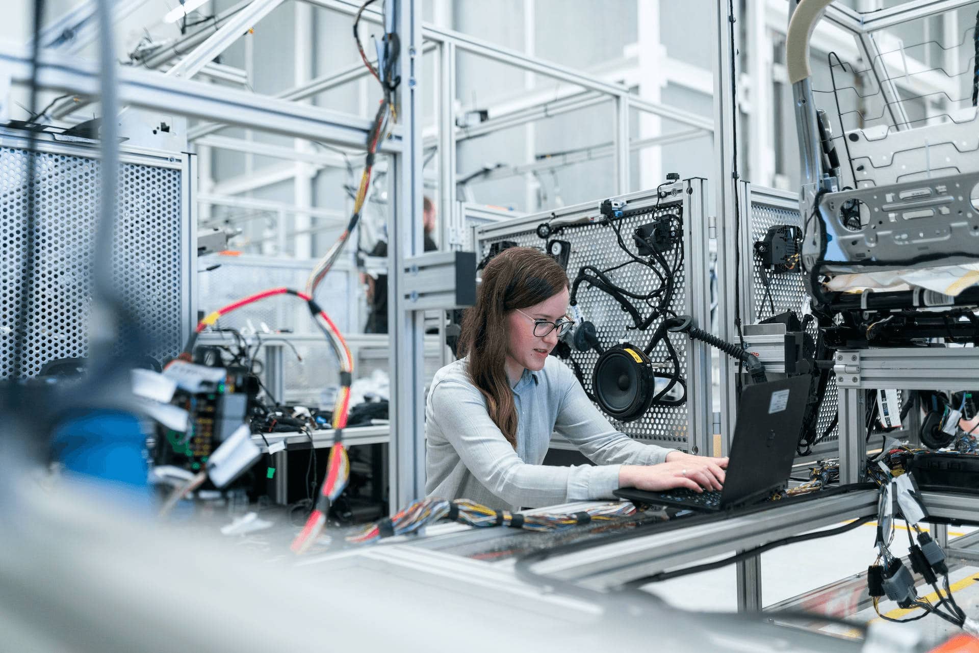 Woman engineer conducting AI testing on a laptop in modern industrial automation setup.