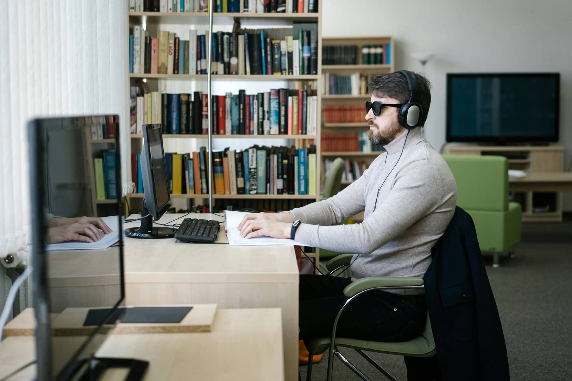 Professional with sunglasses and headphones designing inclusive digital experiences at desk, applying accessibility and UX...