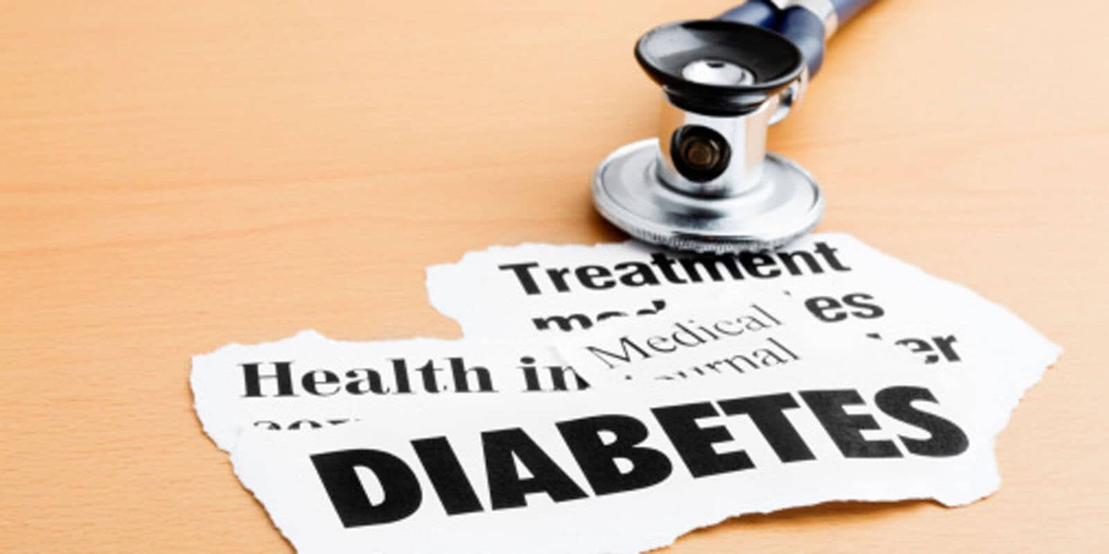 Torn paper with "DIABETES" and "Treatment" text next to a stethoscope on a wooden surface.